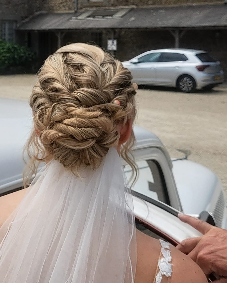 Un chignon tressé de mariée sous le voile, réalisé par Nora
